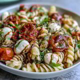 Colorful Caprese-style pasta salad featuring juicy tomatoes, creamy mozzarella, and fragrant basil leaves.