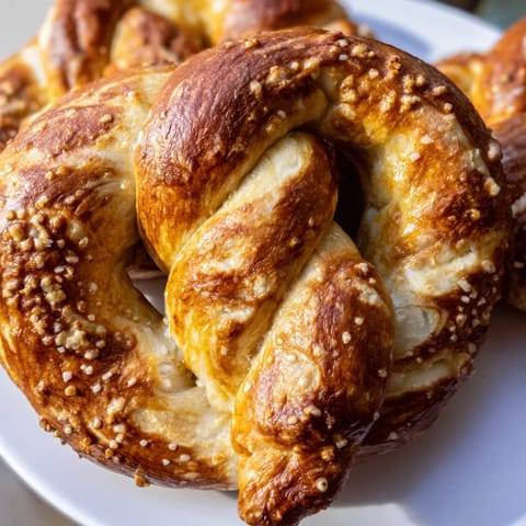 Large, soft-baked pretzels with a chewy interior, sprinkled with coarse salt and arranged on a cooling rack ready for dipping in mustard.