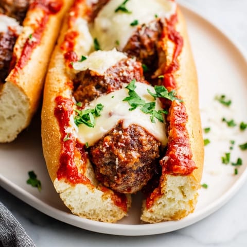 Golden-brown baked meatballs simmering in rich red marinara sauce, ready for assembling into a hearty Meatball Sub.