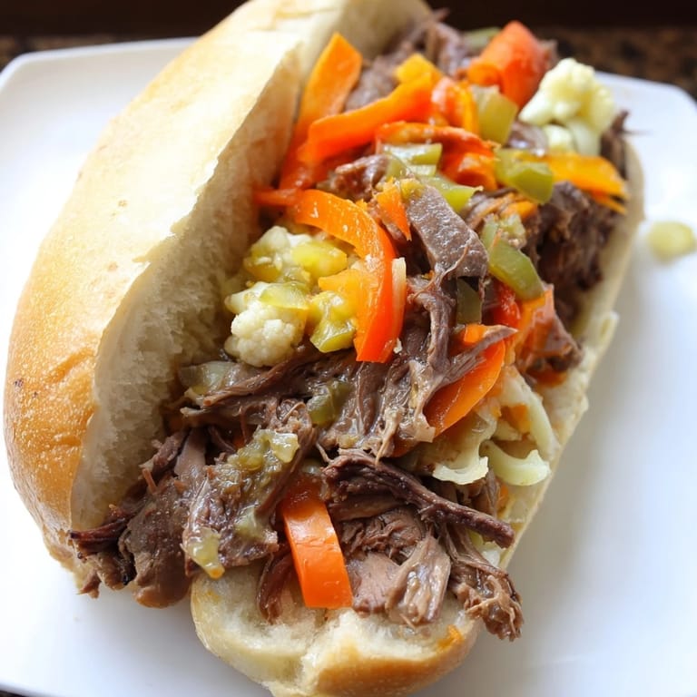Freshly assembled Italian Beef Sandwich with shredded beef and giardiniera on a toasted roll, ready to be dipped in savory au jus.