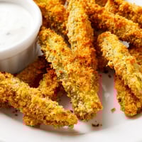 Golden brown, crispy Fried Pickles with ranch dipping sauce on a rustic plate with fresh dill garnish.