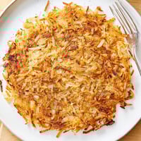 Golden brown shredded hash browns sizzling in a skillet, perfectly crispy for breakfast.